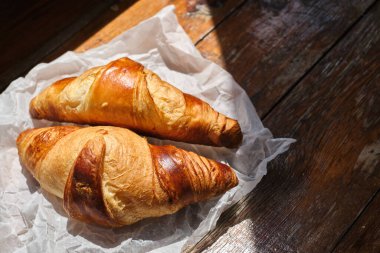 Freshly baked croissant shiny in the rays of the morning sun. Fresh homemade cakes. Delicious traditional french crispy croissants for breakfast