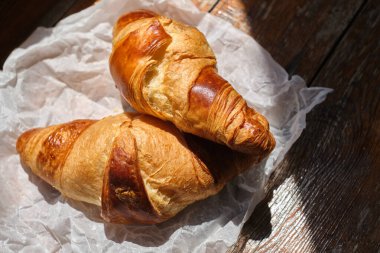Freshly baked croissant shiny in the rays of the morning sun. Fresh homemade cakes. Delicious traditional french crispy croissants for breakfast