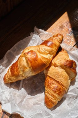 Freshly baked croissant shiny in the rays of the morning sun. Fresh homemade cakes. Delicious traditional french crispy croissants for breakfast