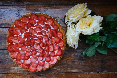 Delicious strawberry tart on a wooden background. Sweet pastry with fresh berries. Sweet dessert for tea and for the holiday