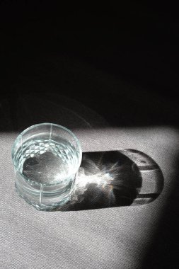 Transparent glass with drinking clean water in the sun on a dark background. The concept of a healthy lifestyle, skin care. A glass of water close-up. Healthy food. Body water balance for health