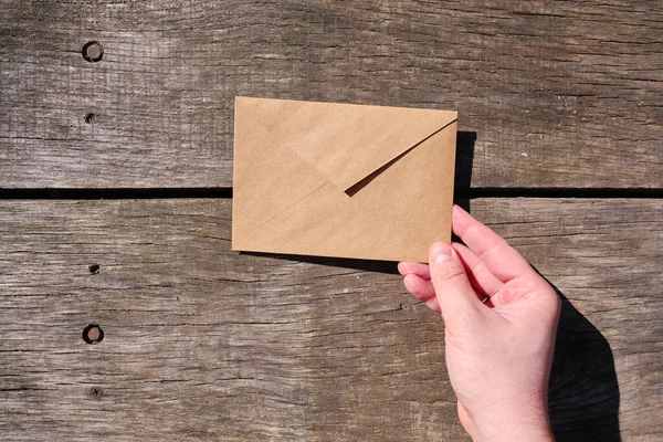 A man holds a paper envelope in his hand. New mail, message. Postal service. The person wants to send or receive a letter. Empty envelope, empty space. The concept of people communication