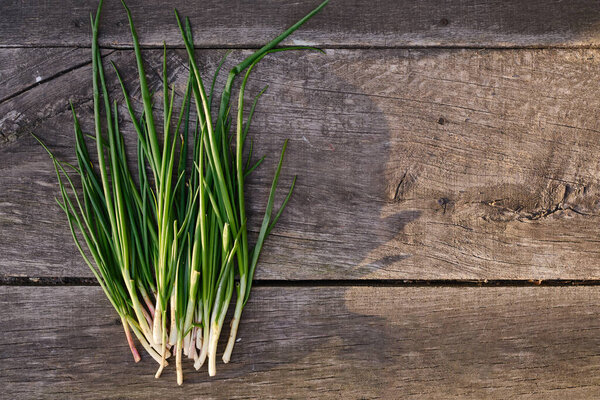Green onions on a wooden background. Ripe organic farm vegetables. Healthy food, vitamins. Bioproducts selected by hand. Seasonal greens from the garden