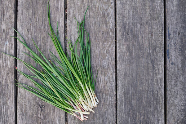 Green onions on a wooden background. Ripe organic farm vegetables. Healthy food, vitamins. Bioproducts selected by hand. Seasonal greens from the garden