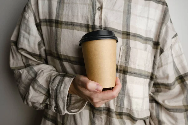 Disposable paper cup close-up. Eco material. Glass for hot drinks. Empty space for text, mockup. Craft paper cup with coffee in a female hand. Coffee to go concept