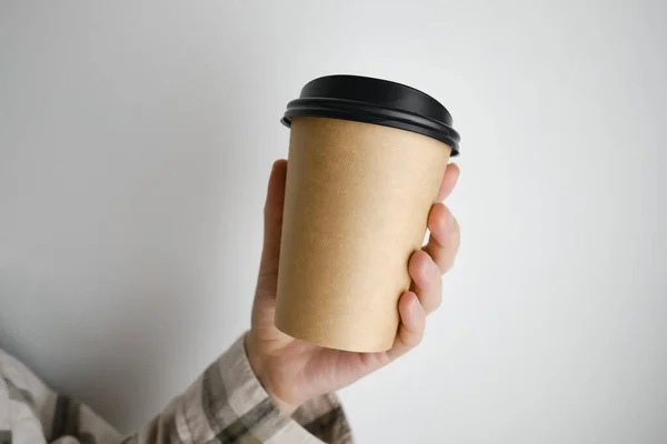 Disposable paper cup close-up. Eco material. Glass for hot drinks. Empty space for text, mockup. Craft paper cup with coffee in a female hand. Coffee to go concept