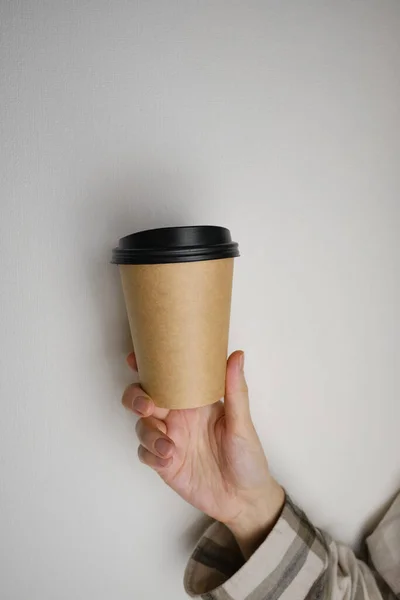 Disposable paper cup close-up. Eco material. Glass for hot drinks. Empty space for text, mockup. Craft paper cup with coffee in a female hand. Coffee to go concept