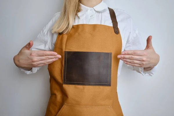 A woman in a kitchen apron. Chef work in the cuisine. Cook in uniform, protection apparel. Job in food service. Professional culinary. Camel fabric apron, casual clothing. Handsome baker posing