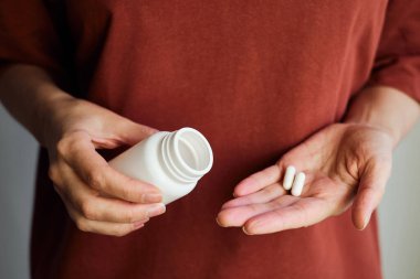 Kadın eline kavanozdan ilaç ya da vitamin döker. Vitamin ya da ilaç alıyordum. Sağlık, ilaç, eczane, hastalık önleme kavramı. Elinde vitamin ya da hap olan bir kavanoz.