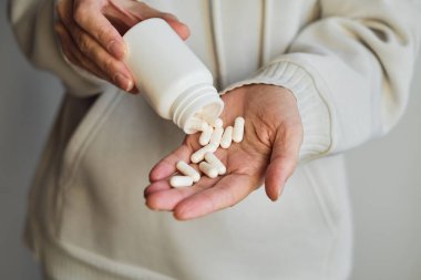 Kadın eline kavanozdan ilaç ya da vitamin döker. Vitamin ya da ilaç alıyordum. Sağlık, ilaç, eczane, hastalık önleme kavramı. Elinde vitamin ya da hap olan bir kavanoz.