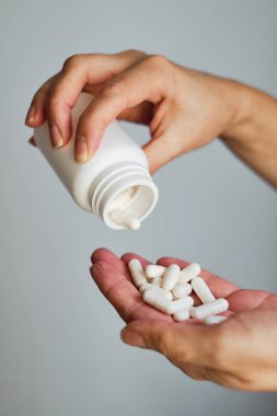 Kadın eline kavanozdan ilaç ya da vitamin döker. Vitamin ya da ilaç alıyordum. Sağlık, ilaç, eczane, hastalık önleme kavramı. Elinde vitamin ya da hap olan bir kavanoz.