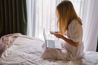 Kız evde ya da otellerde dizüstü bilgisayar ve akıllı telefonla çalışıyor. Mesafeli iş. Ofis evde. Yatak odasındaki kadın dizüstü bilgisayarda yazıyor, uzaklardan öğreniyor, internette sörf yapıyor.