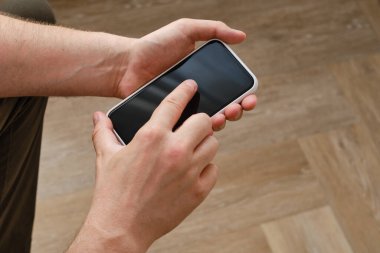 Adam elinde bir telefon tutuyor ve oynuyor ve sonuçtan memnun. Genç bir adam kanepede oturur ve bir aletle eğlenir, bir spor maçı izler. Bir mobil aygıt uygulaması kullanır, metin iletileri gönderir