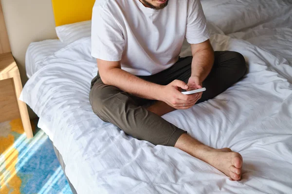 Hombre Tiene Teléfono Inteligente Sus Manos Cama Comprueba Una Cuenta —  Fotos de Stock