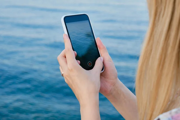 Flickan Håller Smart Telefon Sina Händer Och Tar Bilder Havet — Stockfoto