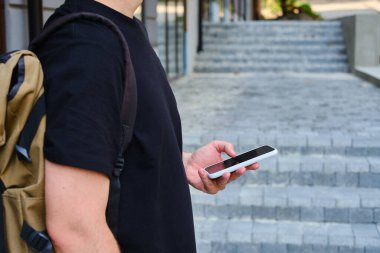 Elinde akıllı telefon olan bir adam iş merkezinin yanında duruyor. Bir işadamı cep telefonunda bir mesaj gönderiyor ya da bir uygulama kullanıyor. Akıllı telefon kapat.