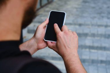 Elinde akıllı telefon olan bir adam iş merkezinin yanında duruyor. Bir işadamı cep telefonunda bir mesaj gönderiyor ya da bir uygulama kullanıyor. Akıllı telefon kapat.