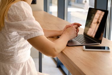 Kız dizüstü bilgisayarın önünde bir masada oturuyor ve iş için akıllı telefon kullanıyor. Evden uzak bir iş. Bilgisayarı ve akıllı telefonu olan bir ofis masası. İş geçmişi. Merkez Ofis