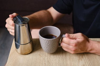 Bir adam moka demliğinde yapılan nefis bir sade kahve içer. Kahvaltıda sabah içkisi. Yakın planda, mis kokulu bir kahve. Kahve yapmak için ekipman.