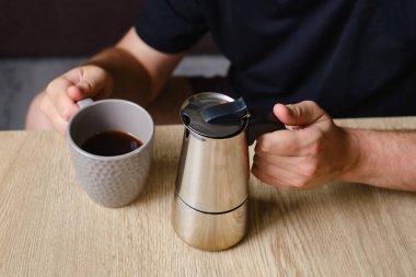 Bir adam moka demliğinde yapılan nefis bir sade kahve içer. Kahvaltıda sabah içkisi. Yakın planda, mis kokulu bir kahve. Kahve yapmak için ekipman.