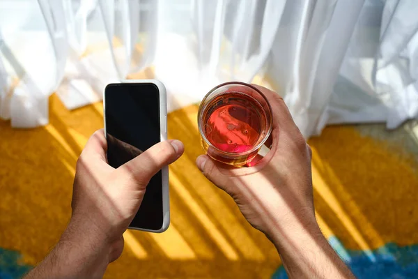 Mannen Tittar Telefonskärmen Och Håller Ett Kristallglas Med Alkohol Smak — Stockfoto