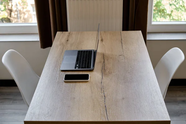 Office desk with laptop and smartphone. Wooden table with several devices. To work remotely. Work from home. Business background. Office at home