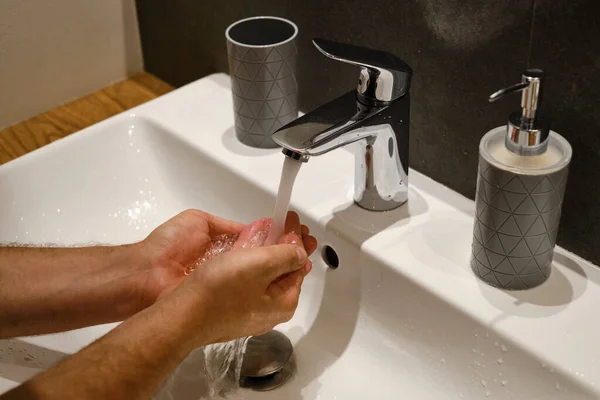 A man washes his hands with water in the bathroom. Human hands close up. Health concept. Keeping your hands clean is the best way to prevent the spread of infection
