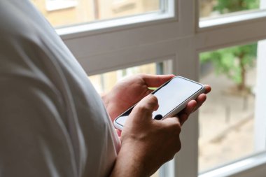 Bir adam elinde modern bir akıllı telefon tutuyor, mesaj gönderiyor ya da cep telefonunda bir uygulama kullanıyor. İş konsepti. Akıllı telefon, yakın plan. Telefon ekranına odaklan.