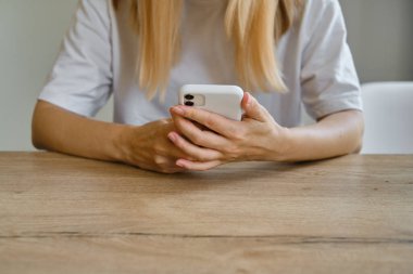 Bir kız elinde modern bir akıllı telefon tutuyor, mesaj gönderiyor ya da cep telefonunda bir uygulama kullanıyor. Gadget bağımlılığı. Akıllı telefon, yakın plan. Telefon ekranına odaklan.