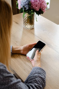 Bir kız elinde modern bir akıllı telefon tutuyor, mesaj gönderiyor ya da cep telefonunda bir uygulama kullanıyor. Gadget bağımlılığı. Akıllı telefon, yakın plan. Telefon ekranına odaklan.