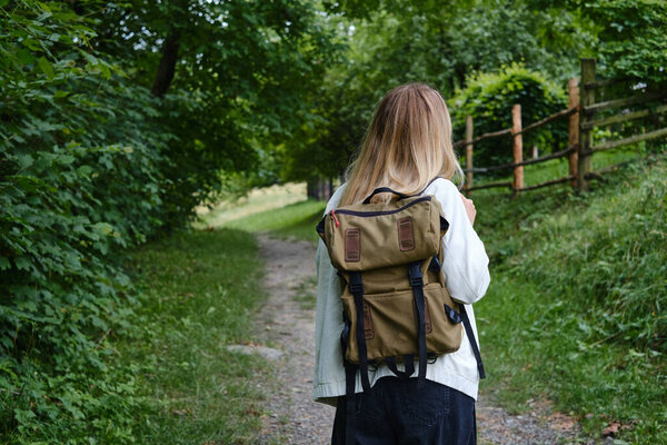 The beautiful girl traveler walks through the village. Beautiful nature landscape in countryside. Hiking journey on tourist trail. Outdoor adventure. Travel and exploration. Healthy lifestyle