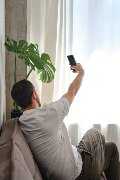 Man takes a selfie on the phone at home or in the office. A young man is talking by video call on a smartphone. Communication and life concept with technologies