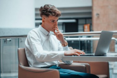 Yakışıklı gülüşü olan genç bir yönetici profesyonel olarak bilgisayarla çalışıyor.