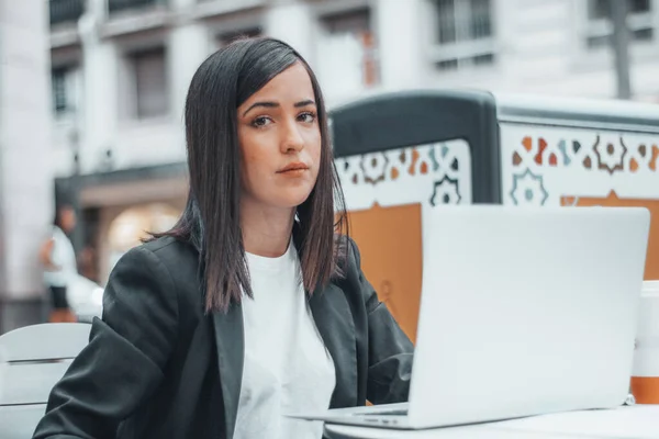 Manager with sadness next to a cafeteria having coffee in a town writing some reports on the laptop or laptop for her company — Stockfoto