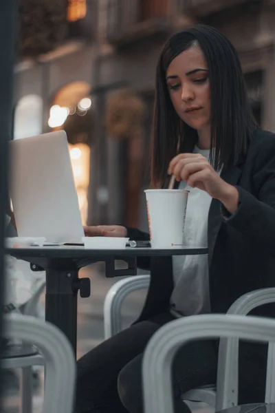 年轻的女商人一边用手提电脑一边在咖啡店里搬咖啡 — 图库照片