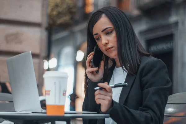 Female entrepreneur manager making an incoming call to one of her clients to agree on a topic informally drinking coffee in the city — Stockfoto