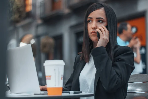 一家重要公司的秘书正在用她的手机等一个电话，在一家正方形的咖啡店里非正式地谈论一件工作中的事情 — 图库照片