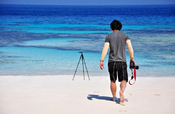 Um homem com câmera digital e tripé na bela praia . — Fotografia de Stock