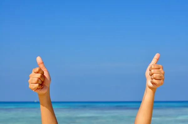 Zwei Hände mit erhobenem Daumen auf blauem Himmel und Meeresgrund lizenzfreie Stockfotos