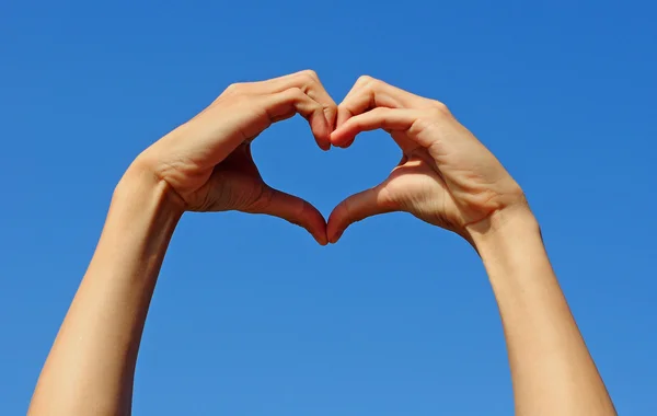 Hand making the sign of Love with the blue sky. Royalty Free Stock Images