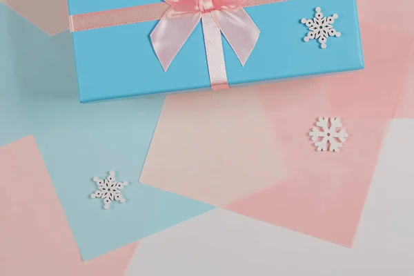 Christmas minimalistic concept. Gift box tied with a ribbon with snowflakes. Flat style, top view, place for text — Stock Photo, Image
