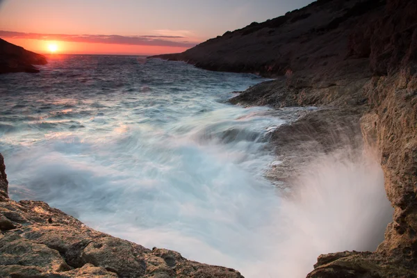 Waves breaking on a rocky seashore at sunset — Stock Photo, Image