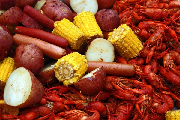 Boiled crawfish with corn, potatoes and hot dogs. — Stock Photo, Image