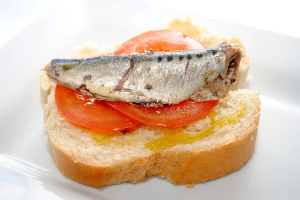 Сардина с оливковым маслом и томатными ломтиками на свежем хлебе — стоковое фото