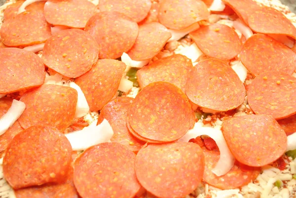 Un montón de pepperoni en un pastel de pizza crudo — Foto de Stock