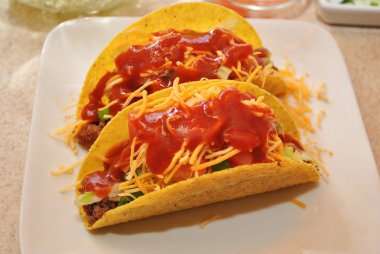 peynir ve sos ile beyaz tabakta iki tacos