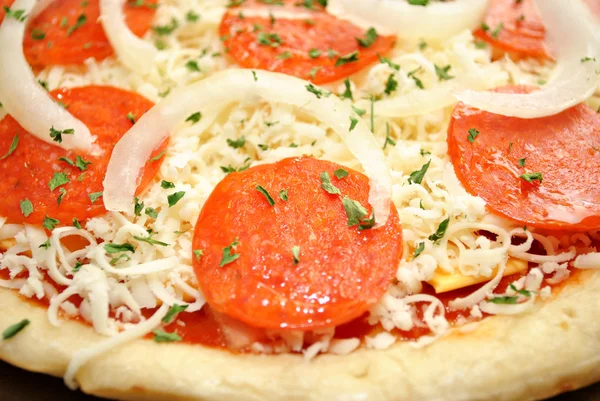 Primo piano di una pizza cruda al salame piccante con cipolle — Foto Stock