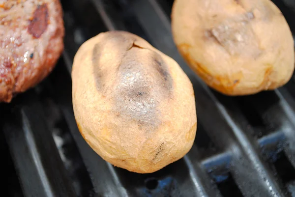 Grelhar batatas inteiras frescas em uma grelha — Fotografia de Stock