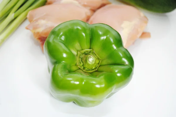 Φωτεινό πράσινο πιπέρι, μπροστά από τους μηρούς ωμός κοτόπουλο — Φωτογραφία Αρχείου