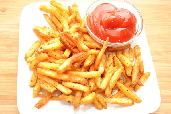 Pittige frietjes geserveerd op een witte plaat met ketchup — Stockfoto